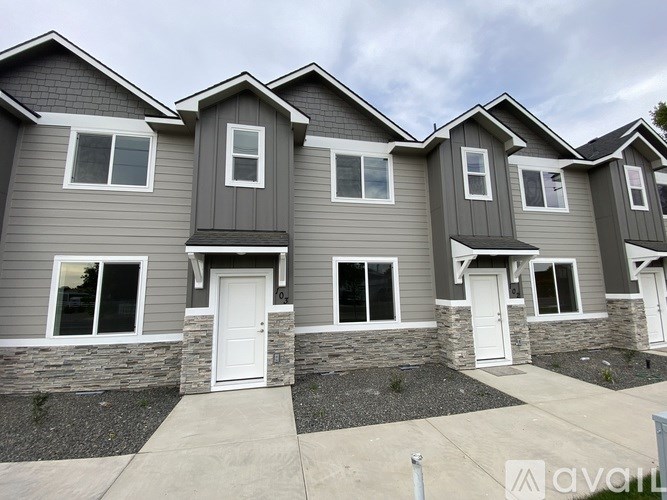 A row of houses with grey siding and white doors.