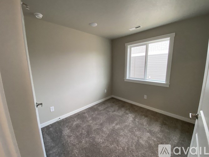 A room with a carpeted floor and a window with blinds.