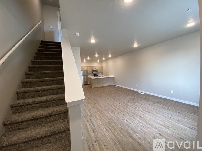 A spacious room with wooden flooring and a staircase leading to another level.