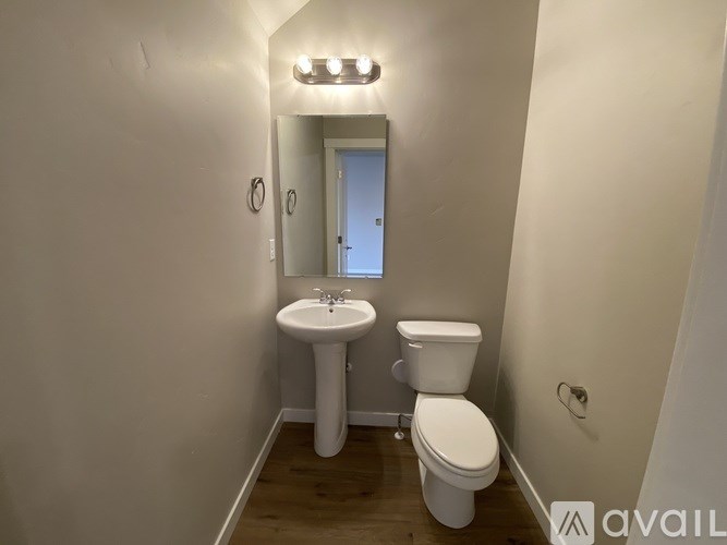 A bathroom with a toilet, sink, and mirror.