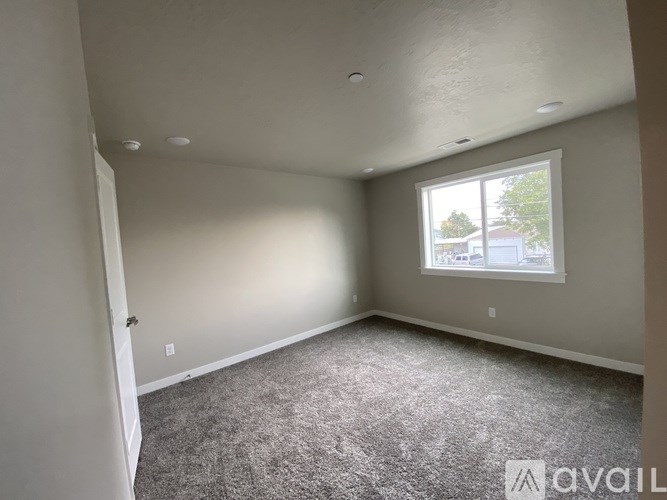 A room with a carpeted floor and a window showing a view of a house.