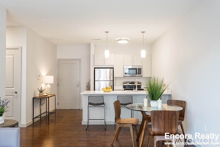 A dining room with a table set for two and a kitchen area in the background.