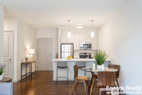 A dining room with a table set for two and a kitchen area in the background.