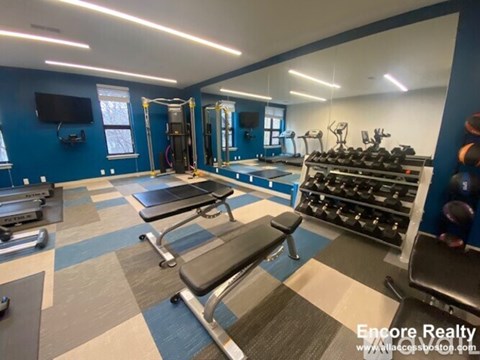 A gym with a variety of equipment including a bench press, a squat rack, and a treadmill.