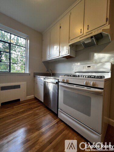 A kitchen with white appliances and wooden floors.