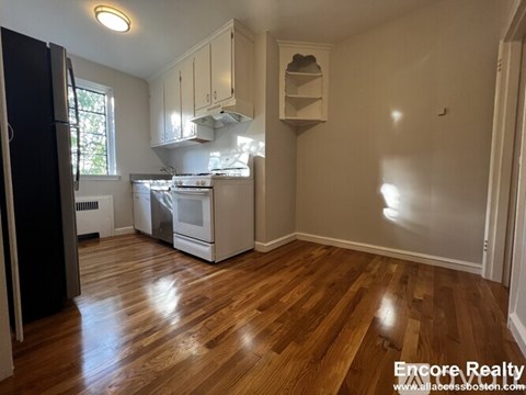 A kitchen with wood floors and white cabinets.