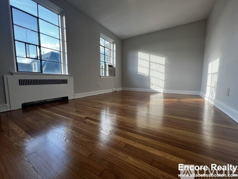 A spacious room with wood flooring and large windows.