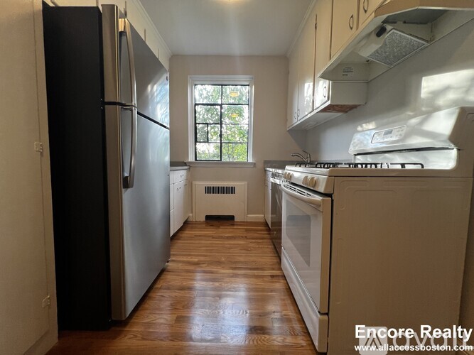 A kitchen with a black refrigerator and white appliances.
