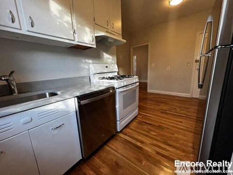 A kitchen with white cabinets and a stove top oven.