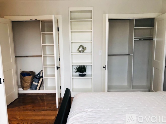 A bedroom with a bed, a wardrobe, and a shelf with a plant on it.