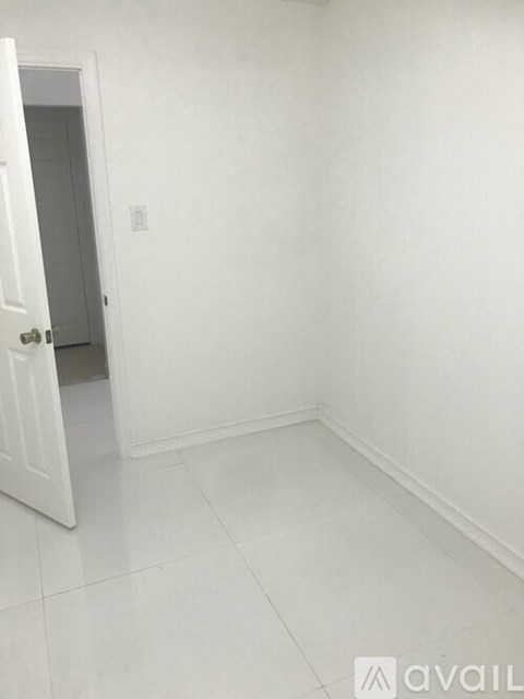 A white room with a door and a light switch on the wall.
