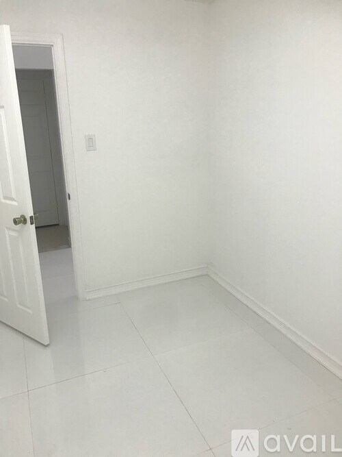 A white room with a door and a light switch on the wall.