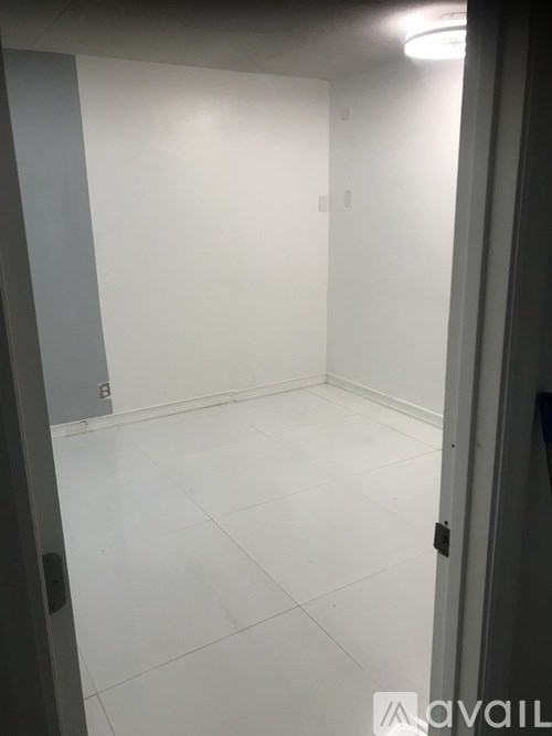 A white tiled room with a door on the right.