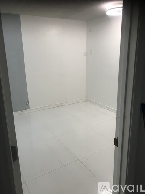 A room with white tiles and a door on the right.