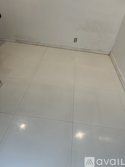 A white tiled floor with a few marks on it.