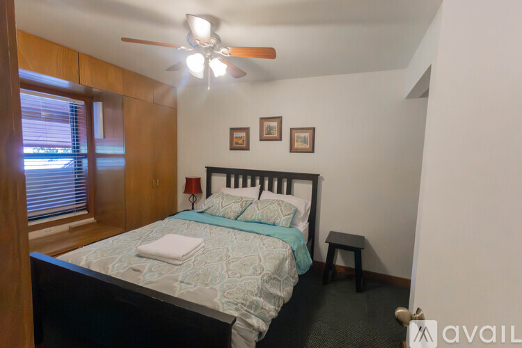 A bedroom with a bed, a ceiling fan, and two pictures on the wall.