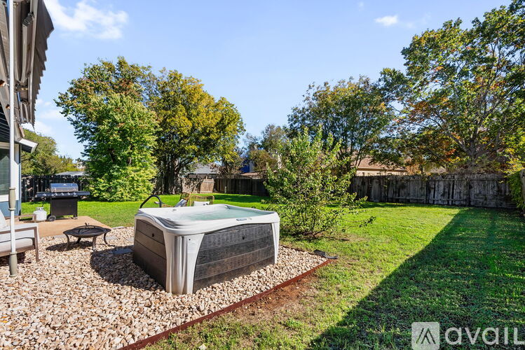 A hot tub is surrounded by a gravel bed in a backyard.