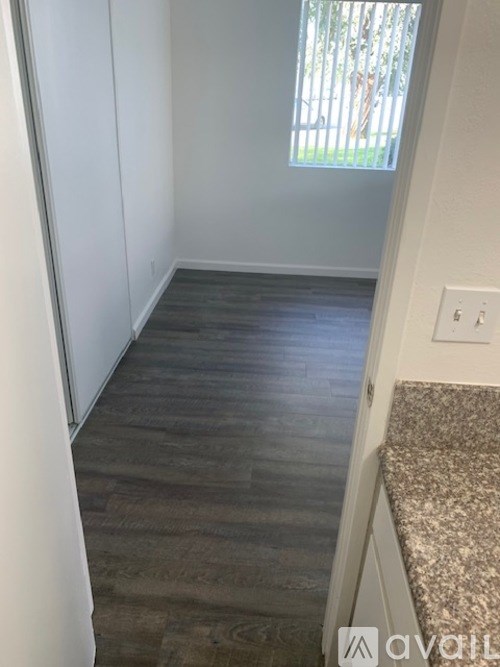 A room with a window and a wooden floor.