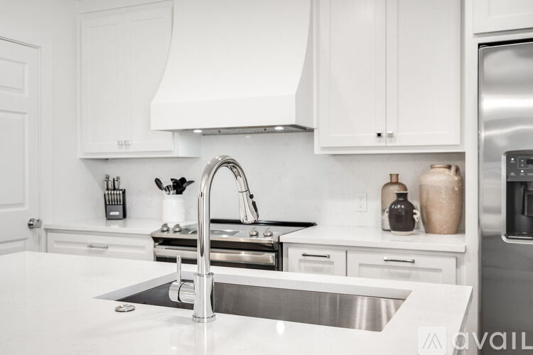 A modern kitchen with white cabinets and a stainless steel sink.