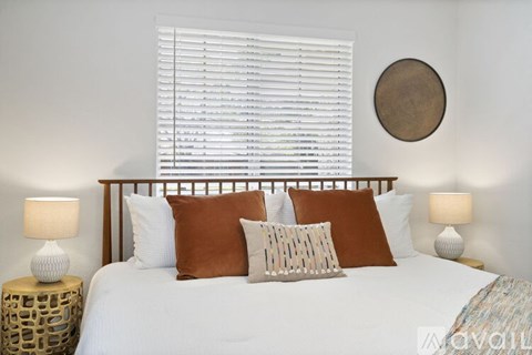 A bedroom with a bed, pillows, and lamps.
