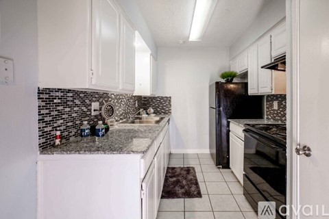 A kitchen with white cabinets and a black fridge.