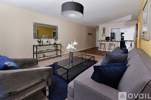 A living room with a grey couch and a glass coffee table.