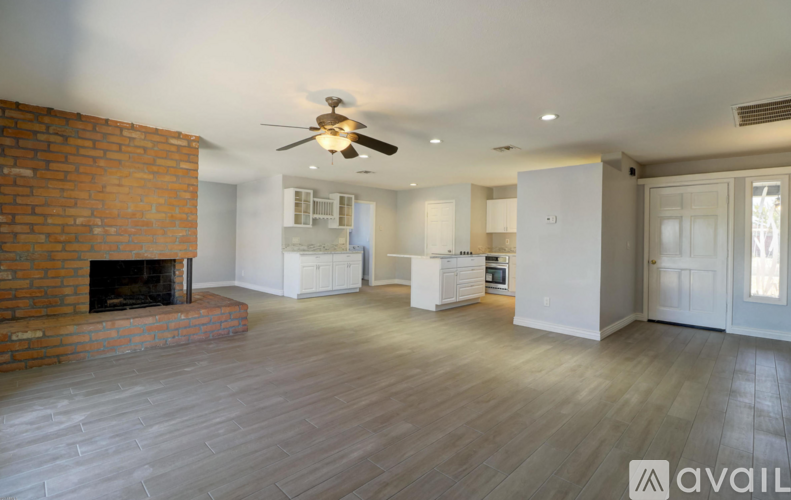 A spacious living room with a brick fireplace and a ceiling fan.
