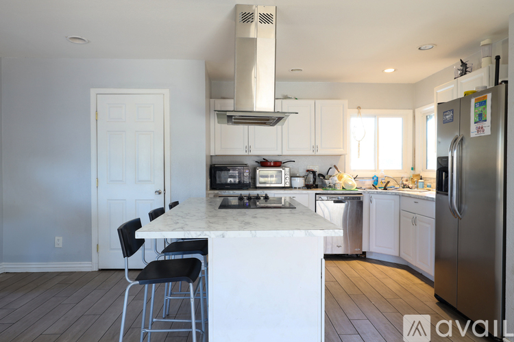 A kitchen with white cabinets and a marble island.