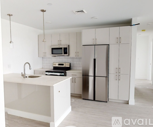 A modern kitchen with a white countertop and stainless steel appliances.