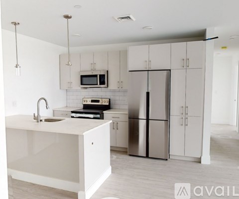 A modern kitchen with a white countertop and stainless steel appliances.