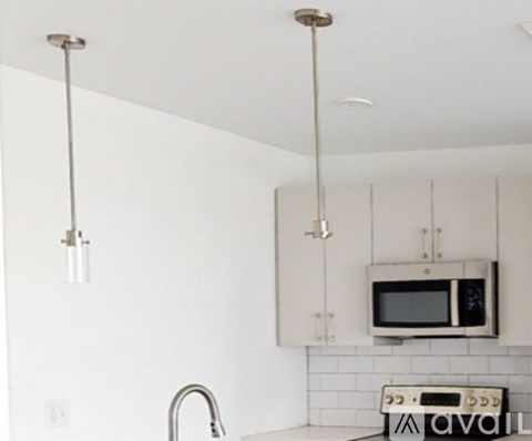A kitchen with white cabinets and a microwave.