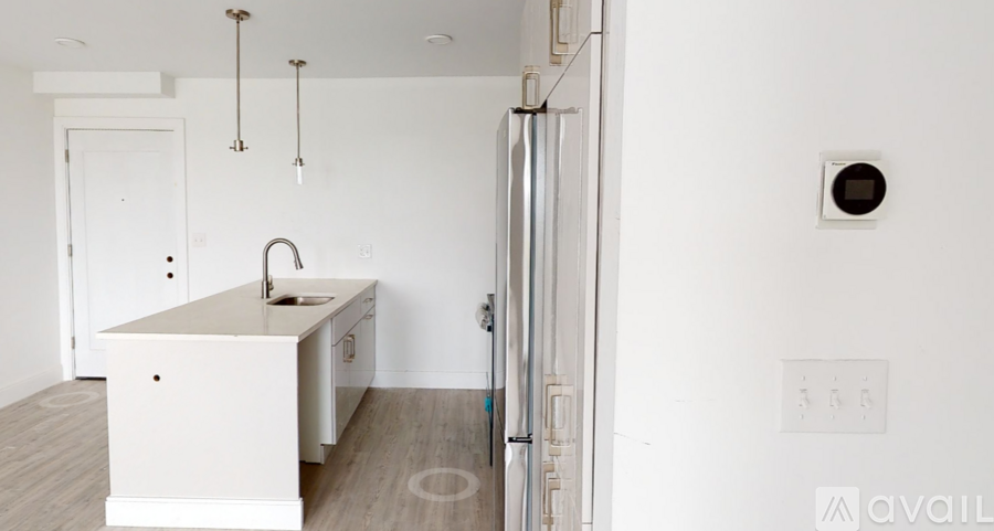 A white kitchen with a sink and a refrigerator.