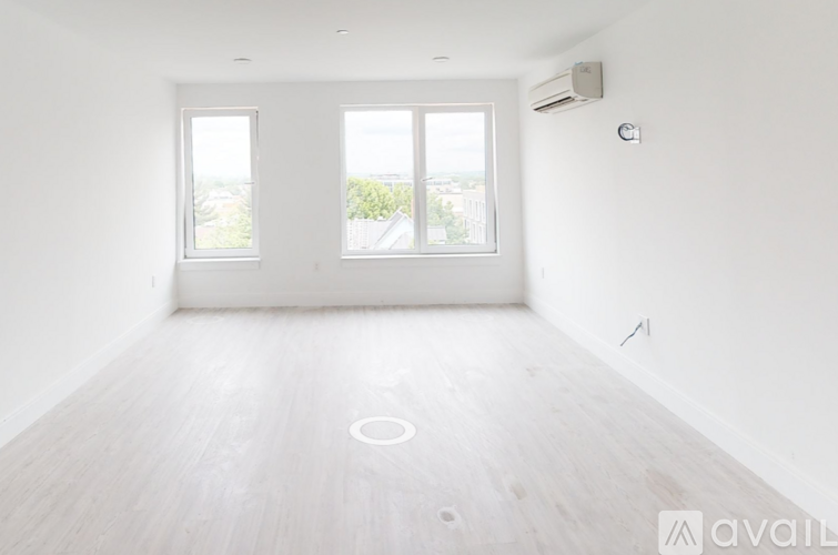 A spacious room with a large window and a wooden floor.