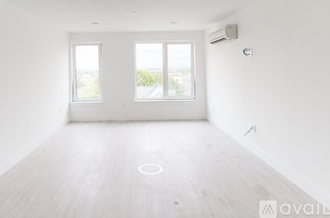 A spacious room with a large window and a wooden floor.