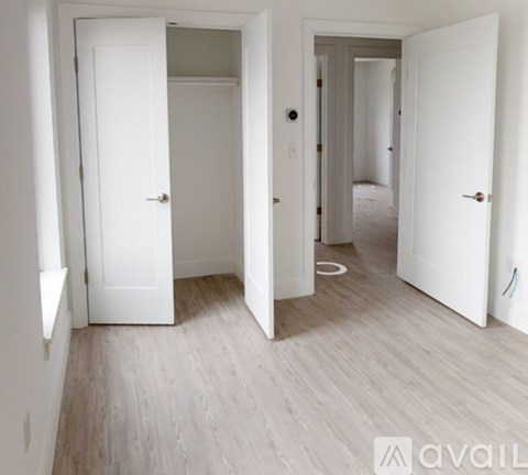 A hallway with white doors and wood flooring.