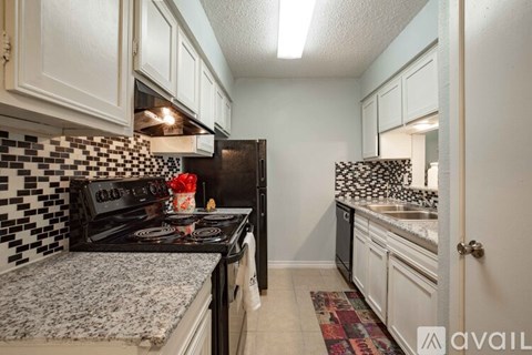 A kitchen with black and white tiles and a black stove top.