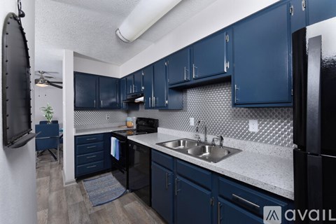 A kitchen with dark blue cabinets and a black refrigerator.