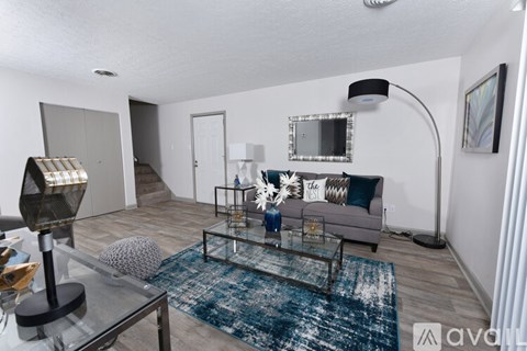 A living room with a glass coffee table and a grey couch.