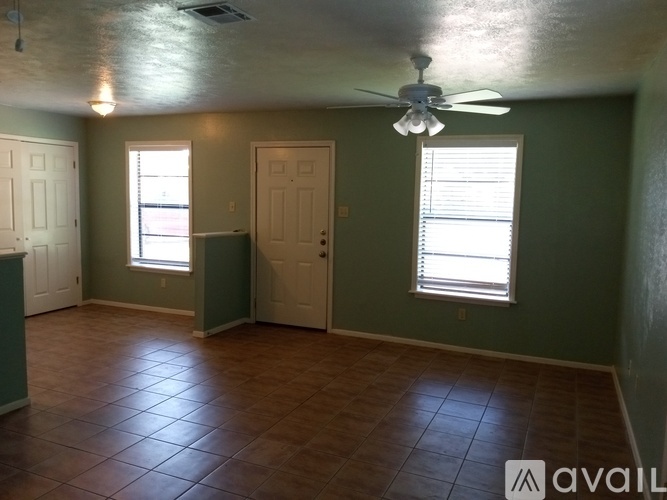 A room with a ceiling fan and two windows.