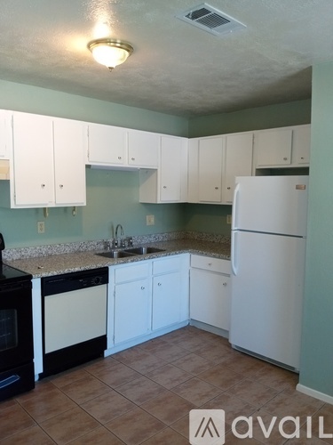 A kitchen with white cabinets and a white refrigerator.