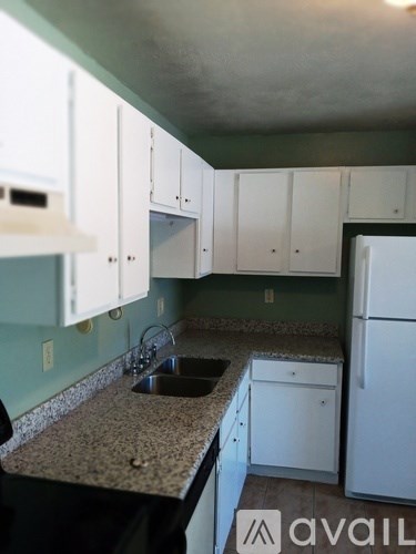 A kitchen with white cabinets and a granite countertop.