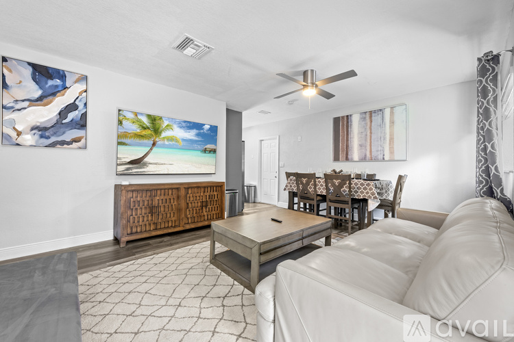 A living room with a painting of a beach scene on the wall.