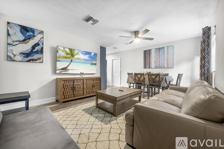 A living room with a painting of a beach scene on the wall.