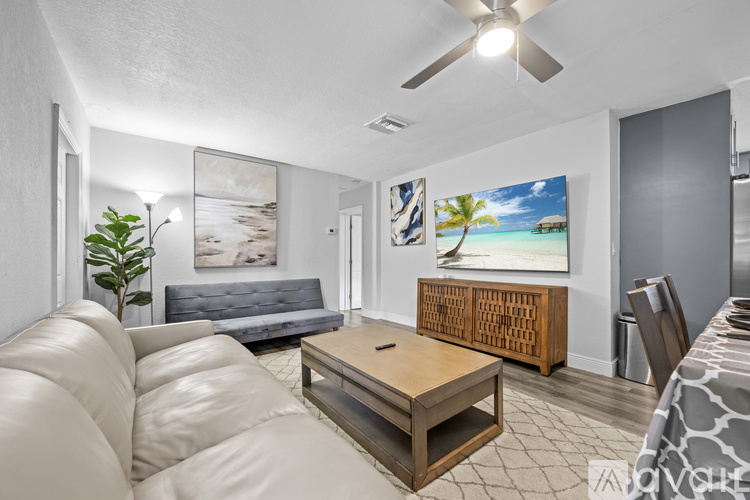 A living room with a white couch and a painting of a beach scene on the wall.