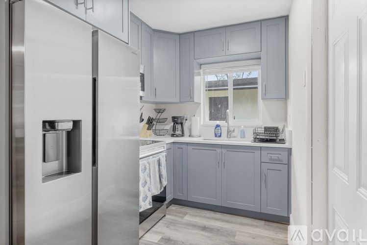 A kitchen with a refrigerator on the left and cabinets above the counter.
