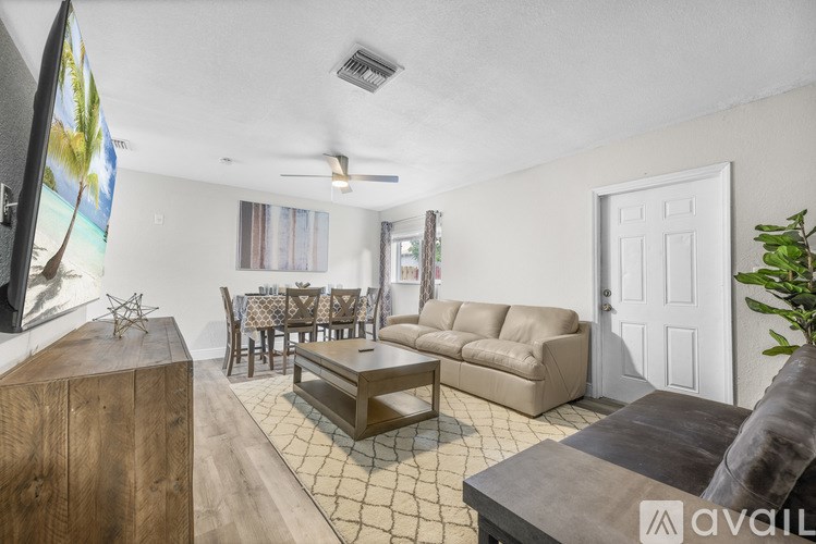 A living room with a wooden cabinet, a grey sofa, a coffee table, and a painting of a beach scene on the wall.