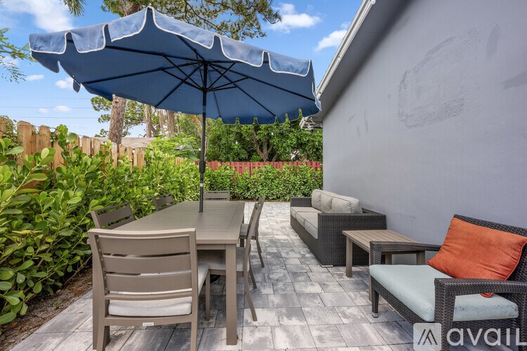 A patio with a grey couch and a wooden table.