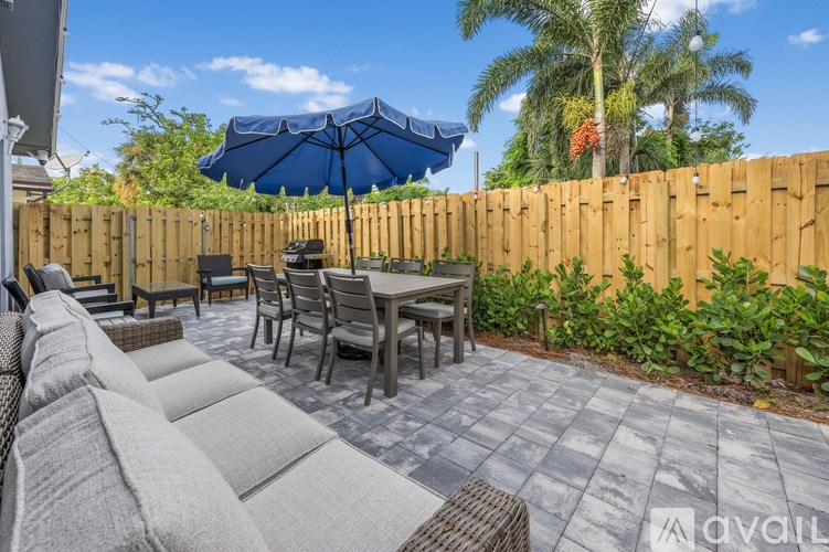 A patio with a table and chairs under a blue umbrella.