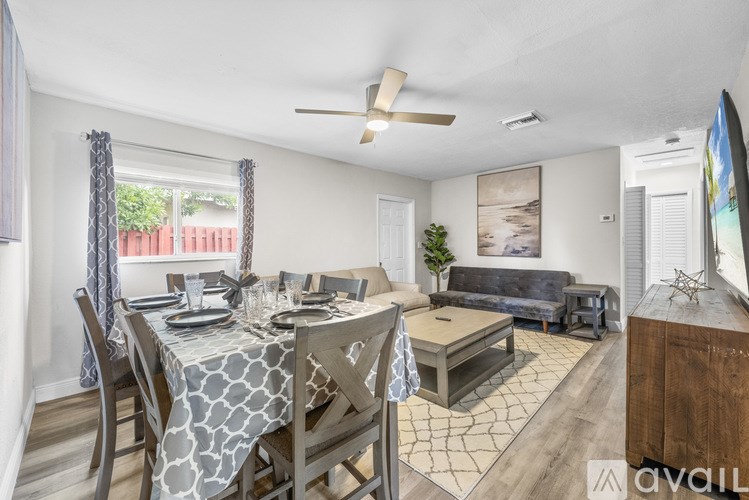 A dining room with a table set for six and a couch in the background.