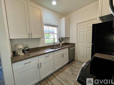 A kitchen with white cabinets and a black refrigerator.